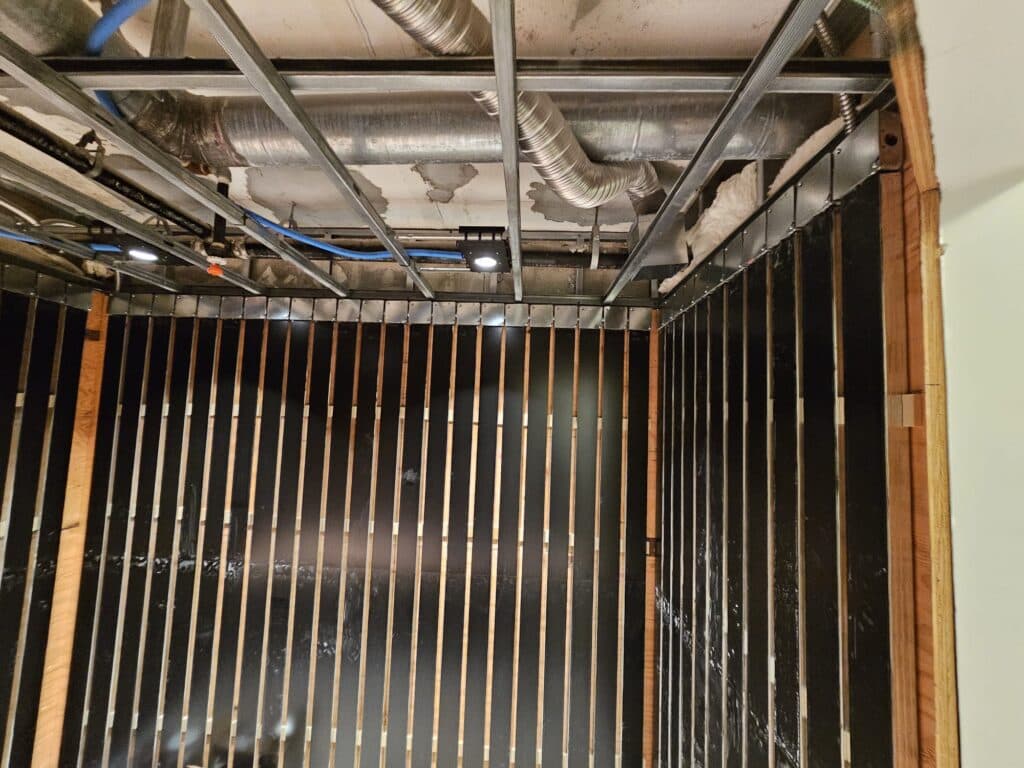 Wood slats and heater panels in an unfinished sauna